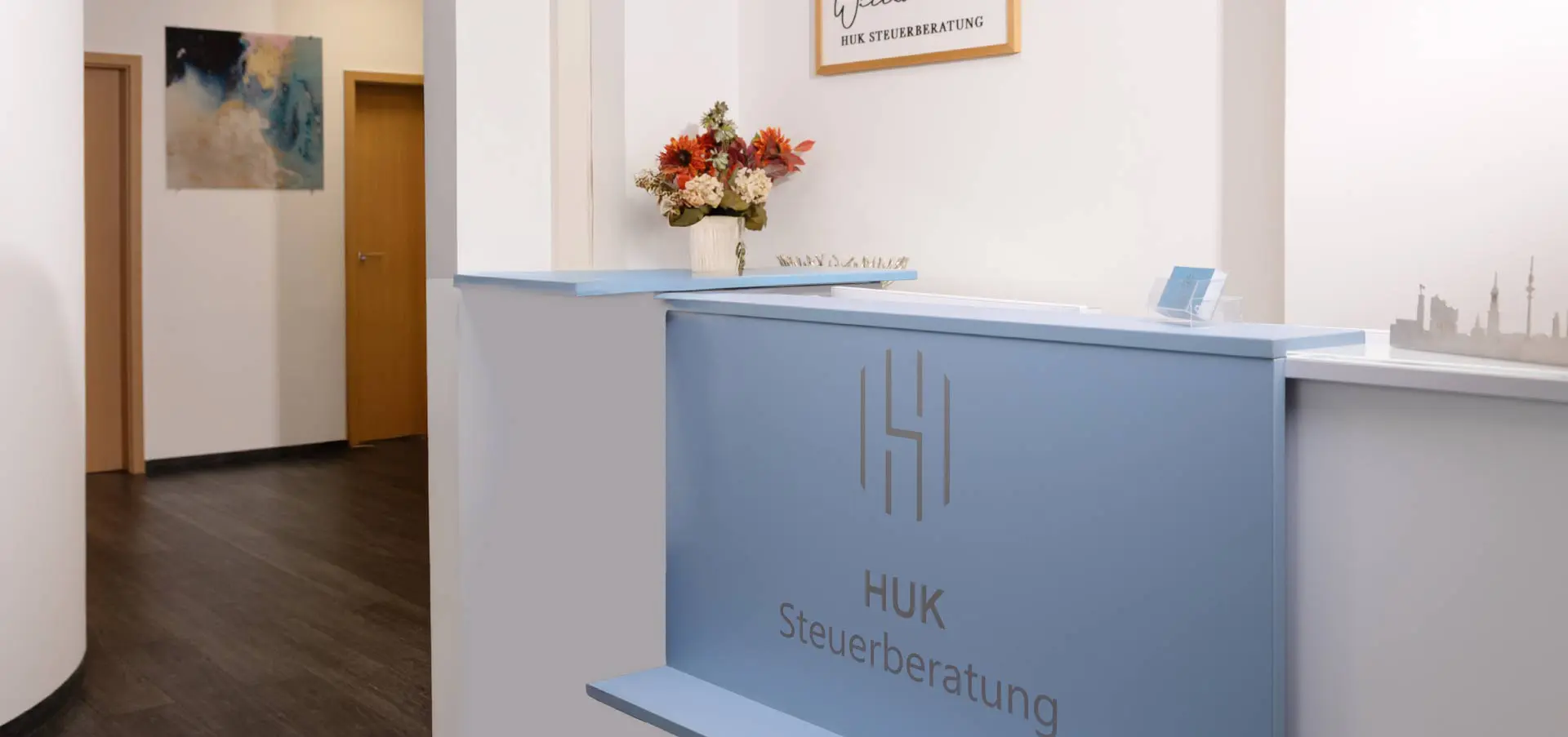 Blick auf den Empfangstresen von Huk Steuerberatung in Hamburg, alles hell und in freundlichen Farben.